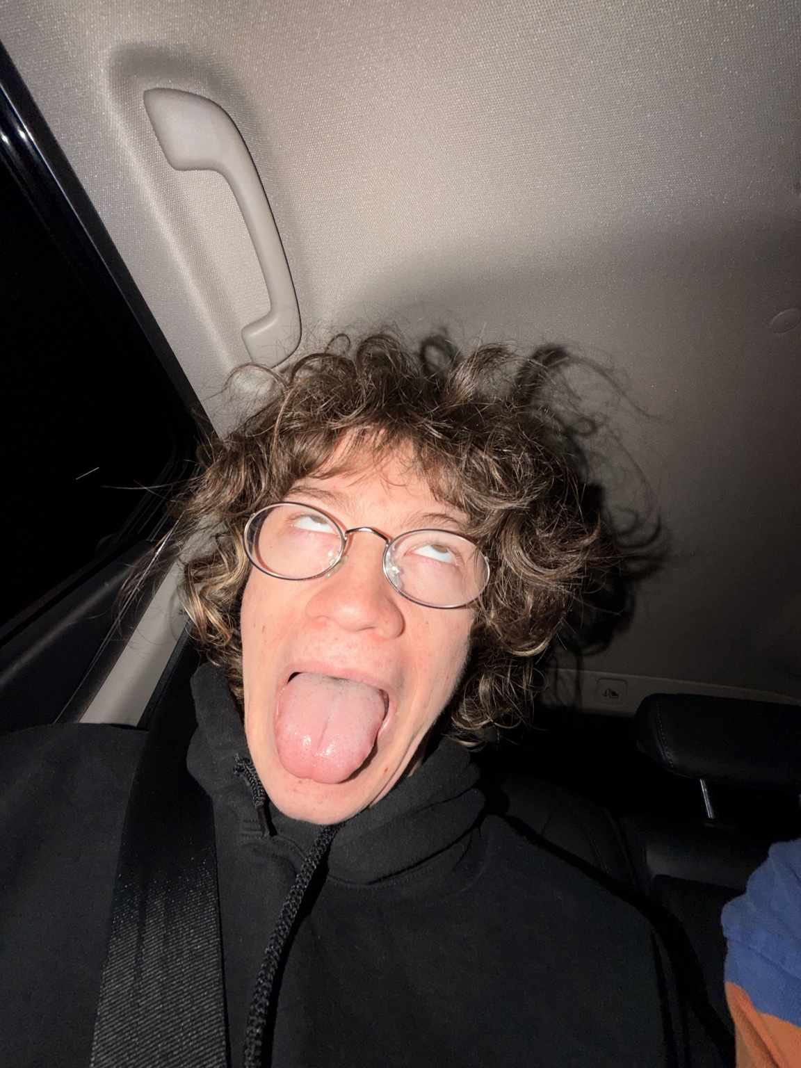 A person with glasses making a silly face in a car